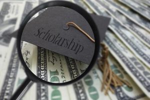 Magnified graduation mortar board with Scholarship text, on money